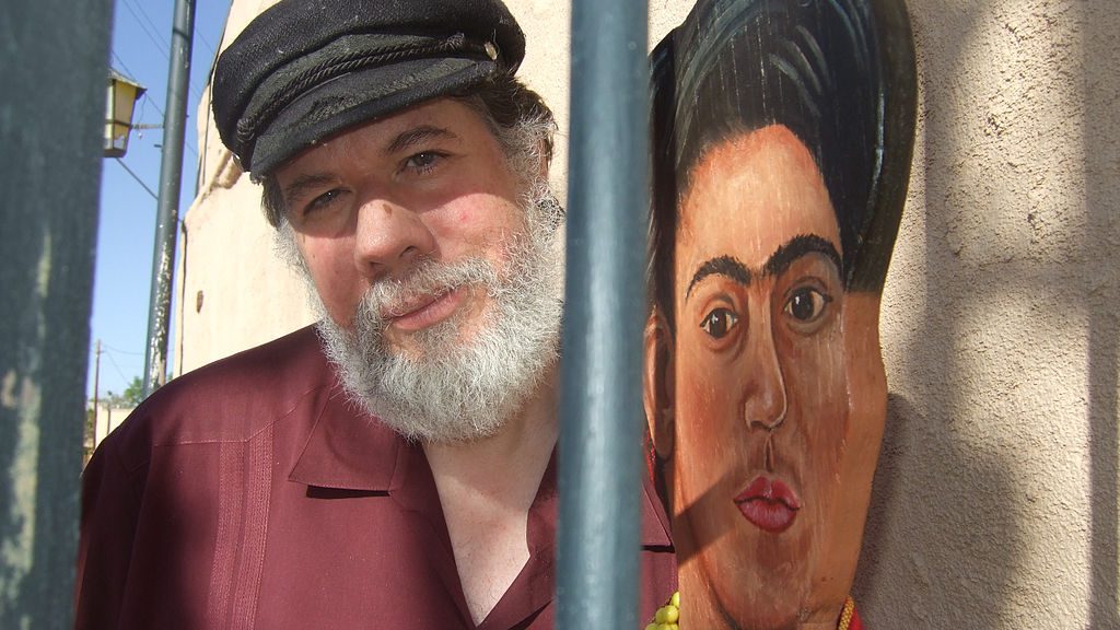 Martin Espada standing next to a mural of Frida Kahlo.
