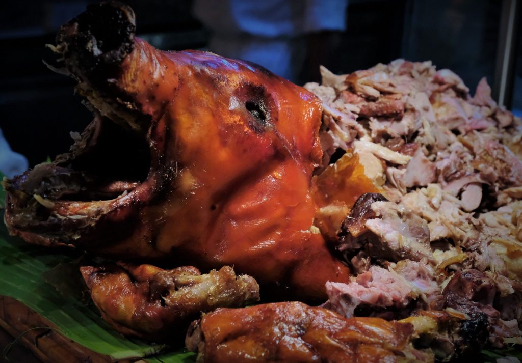 cooked pig head surrounded by cut up meat