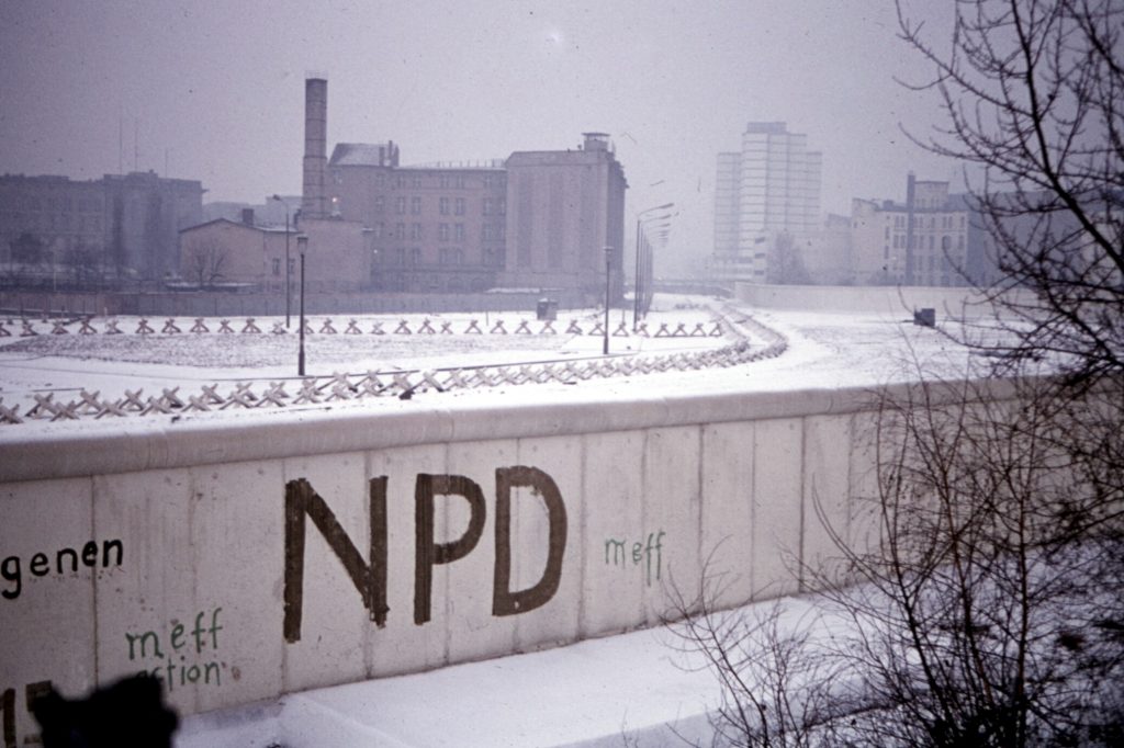 The Berlin Wall on a snowy day with "NPD" graffiti written on it. 