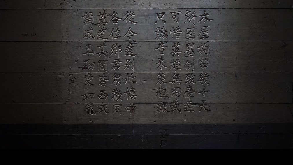 Chinese calligraphy carved into a painted wooden wall